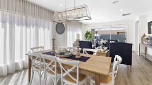 Un comedor moderno con una mesa de madera, sillas blancas y una araña.