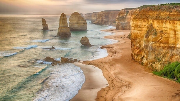 A coastal landscape with prominent rock formations and a sandy beach.