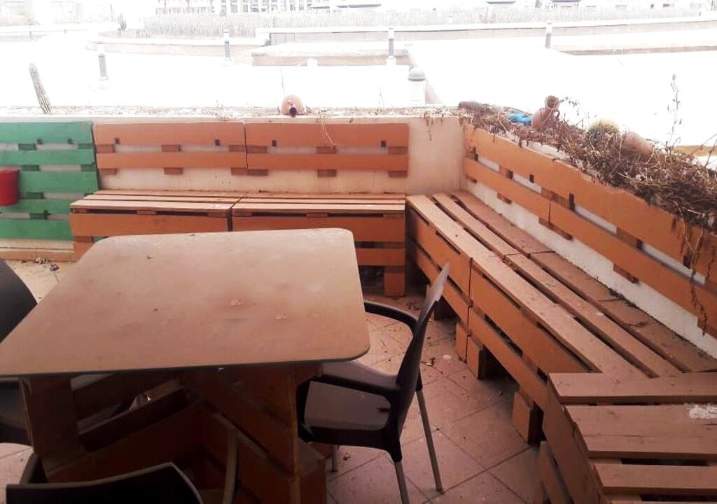 A seating area with wooden benches and a table, likely part of a public space or outdoor restaurant.