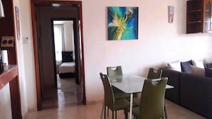 A dining area with a table and chairs, a sofa, and a painting on the wall.