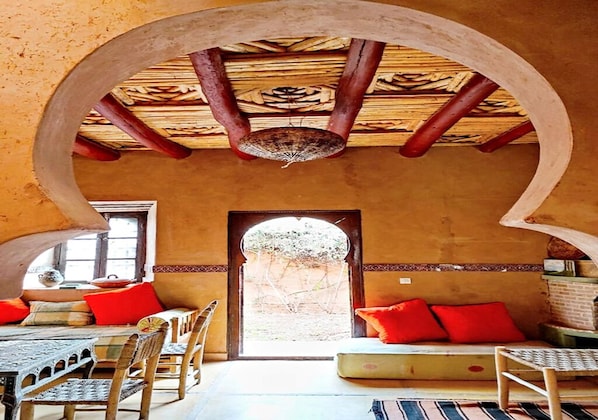 A traditional interior with a wooden ceiling, a large archway, and a view through an open doorway.
