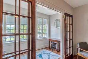 A room with a large window, a desk, a chair, and a rug. - Historic Charlotte Street Condo (Asheville)