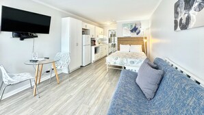 A compact living space with a kitchenette, a dining area, and a bedroom.