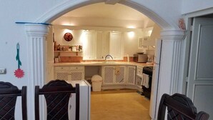 A compact kitchen with white cabinetry, a sink, and a stove. - Charmant Bungalow Tropical (Las Terrenas)