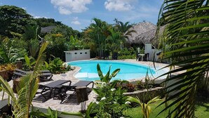 A swimming pool surrounded by lounge chairs and tropical plants. - Charmant Bungalow Tropical (Las Terrenas)