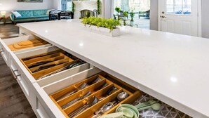 A kitchen with a white countertop, wooden drawers, and a plant on the counter. - Breakfast with a View with BBQ Firepit Golf Course (Conroe)