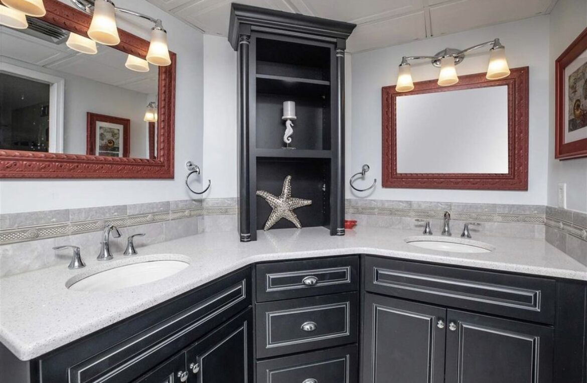 A bathroom with two sinks, black cabinetry, and a starfish decoration.