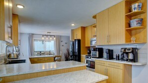 Una cocina moderna con armarios de madera, encimera de mármol y electrodomésticos de acero inoxidable.