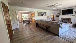 Una sala de estar con sofá, televisión, chimenea y un comedor con sillas y mesa.