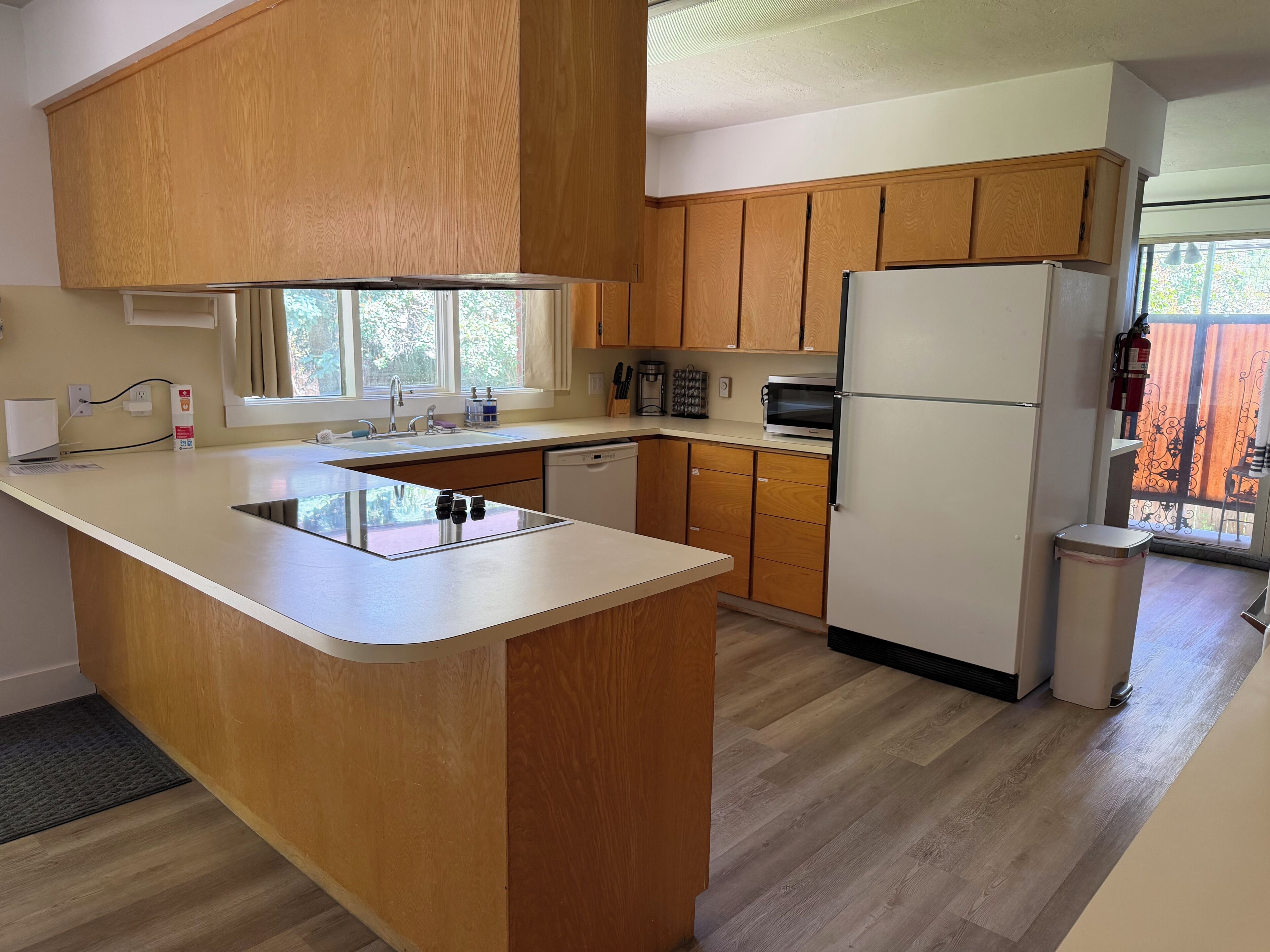 Una cocina con armarios de madera, una isla integrada, un refrigerador y una ventana con vistas.