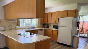 Una cocina con armarios de madera, una isla integrada, un refrigerador y una ventana con vistas.