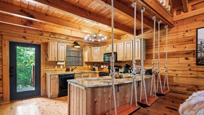 Cocina de cabaña de madera con una isla central, armarios de madera y una lámpara colgante.