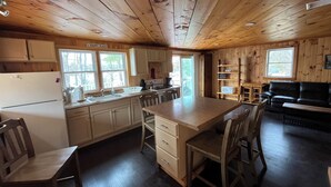 A spacious kitchen with wooden cabinets, a central island, and a dining area with chairs.