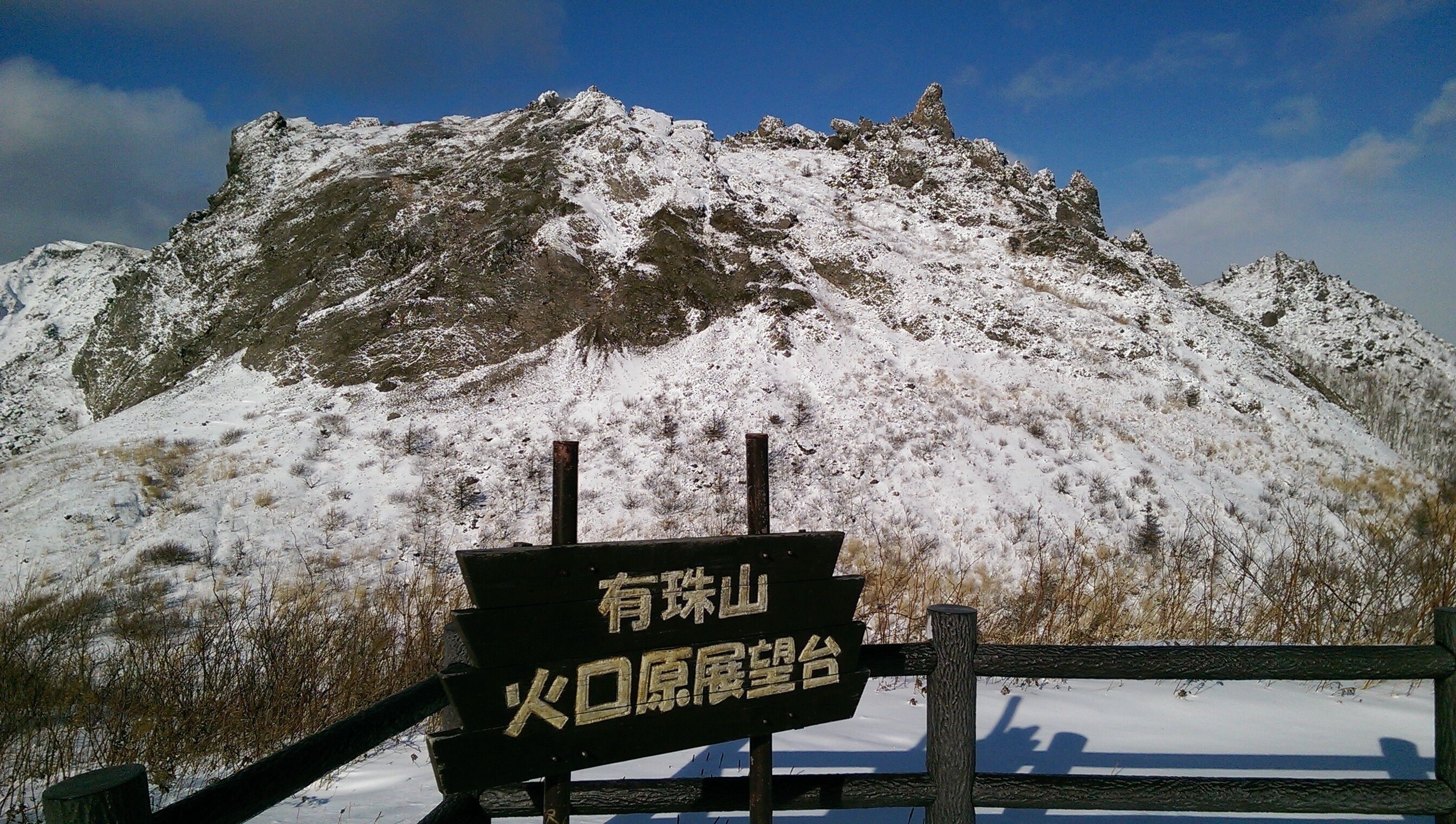 A sign with Chinese characters in front of a snow-covered mountain.