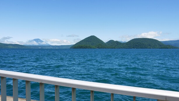 A view of a body of water with a distant mountain range and a clear sky. - Kohan no yado Kojima (Toyako)