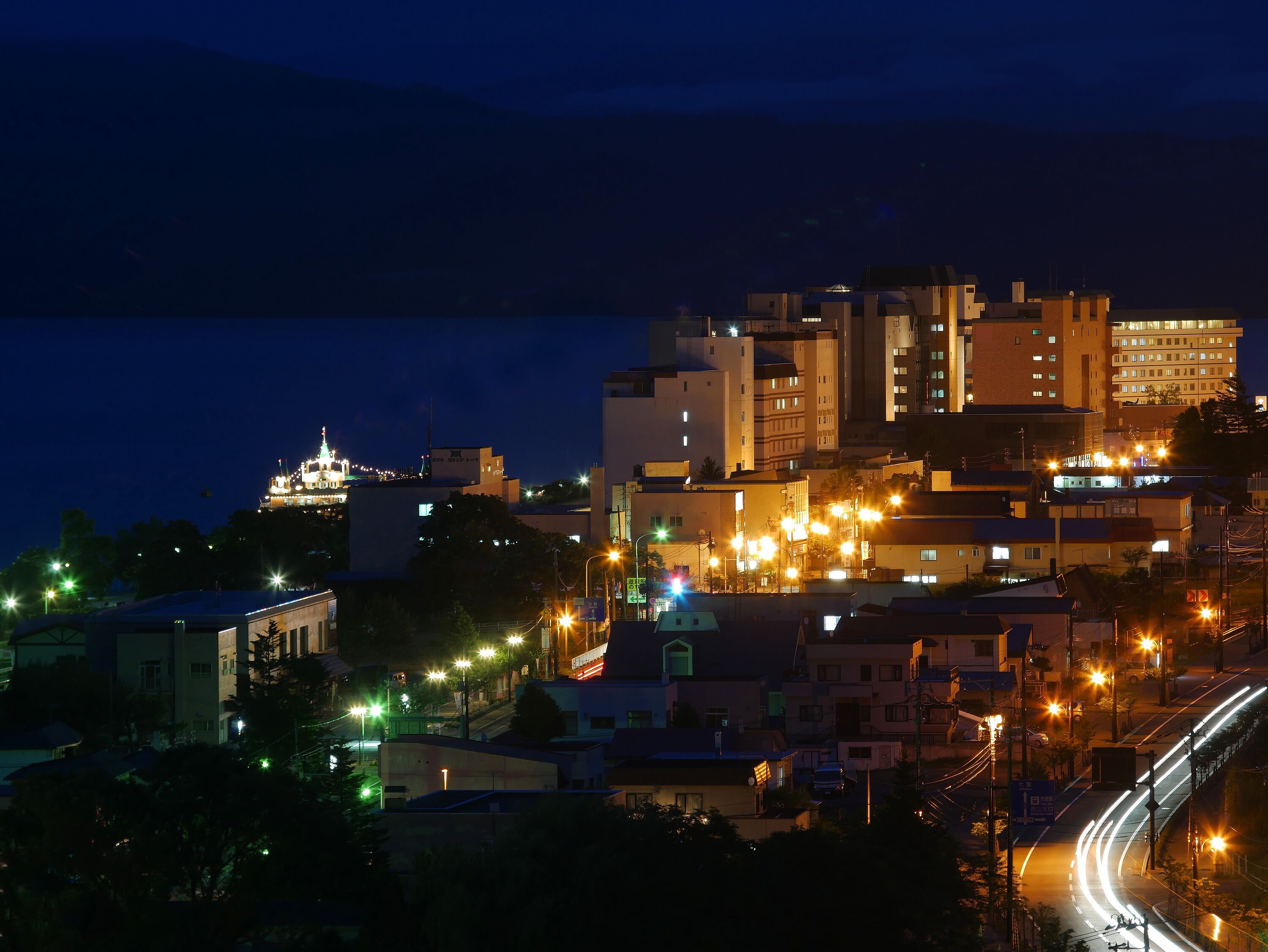 A nighttime cityscape with illuminated buildings and a prominent church spire.