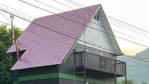 A two-story building with a sloped roof, a balcony on the upper floor, and a small porch area. - Kohan no yado Kojima (Toyako)