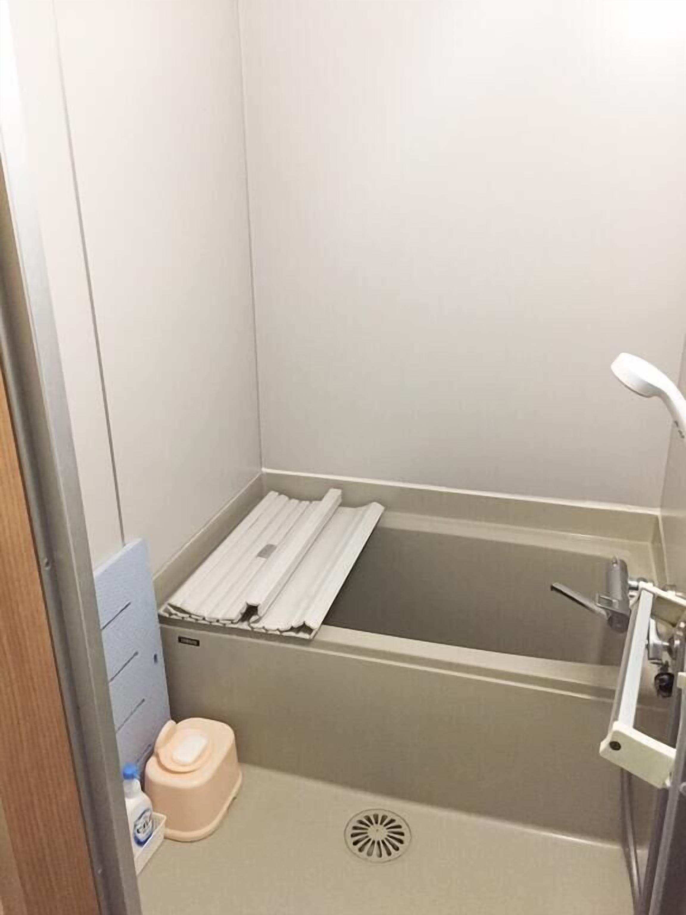 A small, narrow bathroom with a bathtub, a toilet, and a shower.