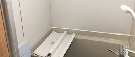 A small, narrow bathroom with a bathtub, a toilet, and a shower.