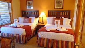 Une chambre d’hôtel avec deux lits, chacun recouvert d’une couvre-lit à rayures rouges et blanches, et dotée d’une tête de lit en bois. Une table de chevet avec une lampe se trouve entre les deux lits.