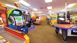 Une salle d’arcade intérieure proposant divers jeux, notamment un flipper et plusieurs bornes d’arcade.