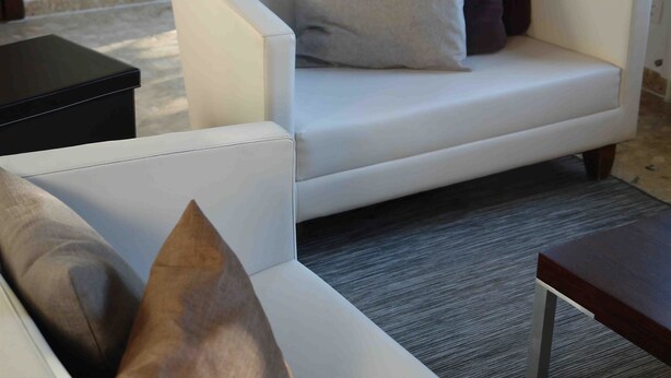 Ein weißes Sofa mit dunklem und hellem Kissen, ein kleiner schwarzer Tisch und ein grauer Teppich.