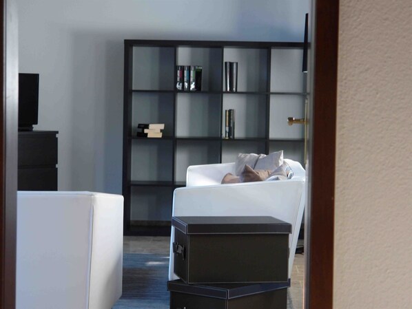 A modern living room with a white sofa, a black entertainment unit, and a bookshelf.