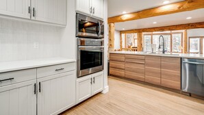 Una cocina moderna con armarios blancos, electrodomésticos de acero inoxidable y una viga de techo de madera.