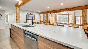 Una cocina amplia con una isla grande, vigas de madera y vistas al exterior a través de amplios ventanales.