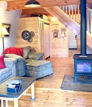 Ein gemütliches Wohnzimmer mit einer Couch, einem Couchtisch, einem Kamin und einer Treppe.