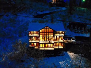 A multi-story building with large windows and a snow-covered roof, surrounded by trees and a snowy landscape.
