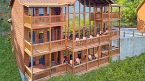 A multi-story wooden cabin with balconies, situated by a lake.