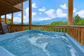 A hot tub on a wooden deck with a mountain view.