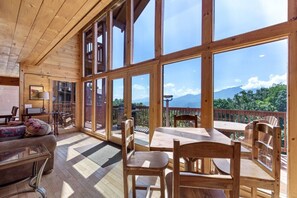 A wooden cabin with a large deck, a dining area, and a sofa.