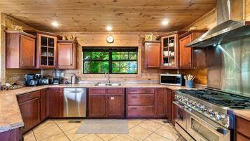 A kitchen with wooden cabinets, a stainless steel stove, and a window with a view of greenery.