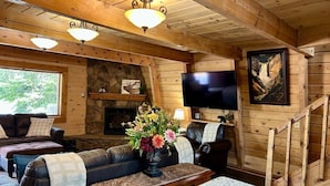 A wooden cabin interior with a stone fireplace, a television, a sofa, and a dining table. - Trailer Parking *Dog Friendly* Fireplace (Island Park)