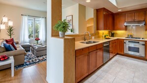 A modern kitchen with wooden cabinets, stainless steel appliances, and a central island. - Condo in Trendy Neighborhood Within Walking Distance to Beach! (Santa Barbara)