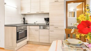 Une cuisine moderne avec des meubles de couleur bois clair, un four encastré, un lave-vaisselle et une machine à café.