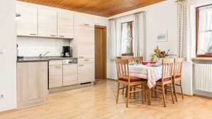 Une cuisine moderne avec des meubles en bois, une machine à café et un coin repas avec une table dressée pour quatre personnes.