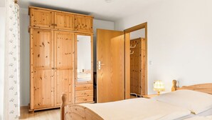 Une chambre à coucher avec une armoire en bois, un lit et une table de chevet avec une lampe.