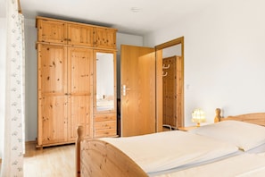 A bedroom with a wooden wardrobe, a bed, and a nightstand with a lamp. - Vacation apartment 3, 42 sqm with 1 bedroom, kitchen-living room, balcony (Piding)