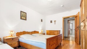 Quarto com cama de madeira, mesas de cabeceira, guarda-roupa de madeira e porta para um banheiro.