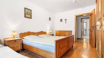 Ein Schlafzimmer mit einem hölzernen Bett, Nachttischen, einem Holzschrank und einer Tür zu einem Badezimmer.