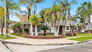 A residential neighborhood with houses featuring stucco exteriors, palm trees, and a well-maintained lawn.