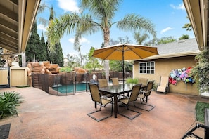 A covered patio with a pool, outdoor furniture, and a variety of plants.