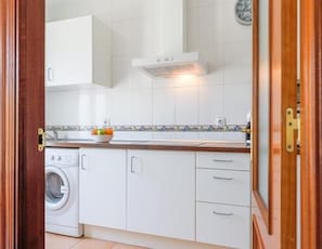 Enjoy a practical kitchen with washing machine, tiled backsplash, and ample countertop space.