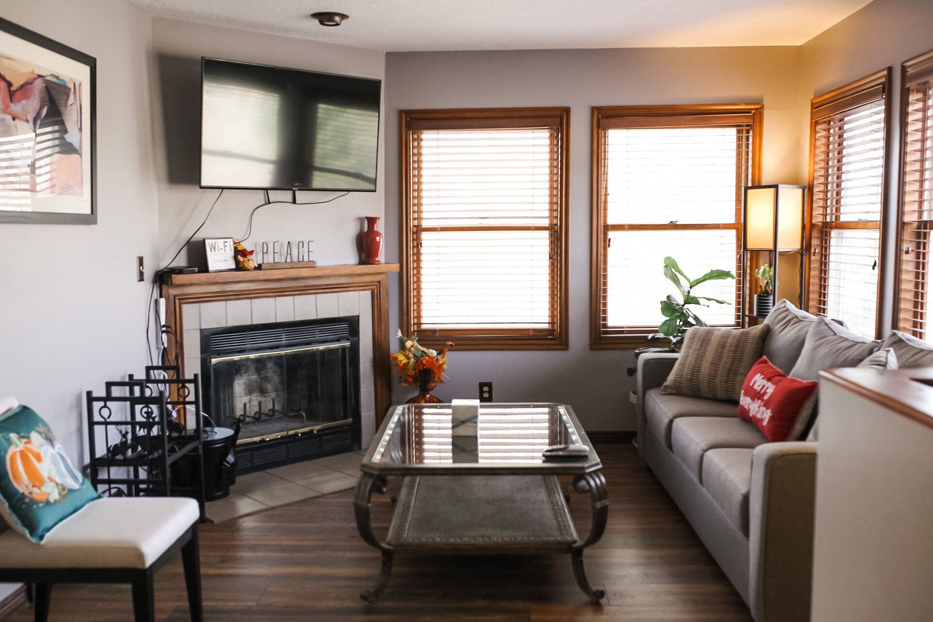 A living room with a fireplace, a sofa, a coffee table, and two windows with blinds.
