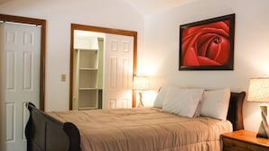 Een slaapkamer met een bed, nachtlampjes, een lijst met een roos en een kledingkast.