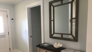Un pasillo con una consola de madera, un espejo y una puerta.