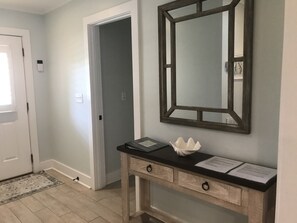 A hallway with a wooden console table, a mirror, and a door.